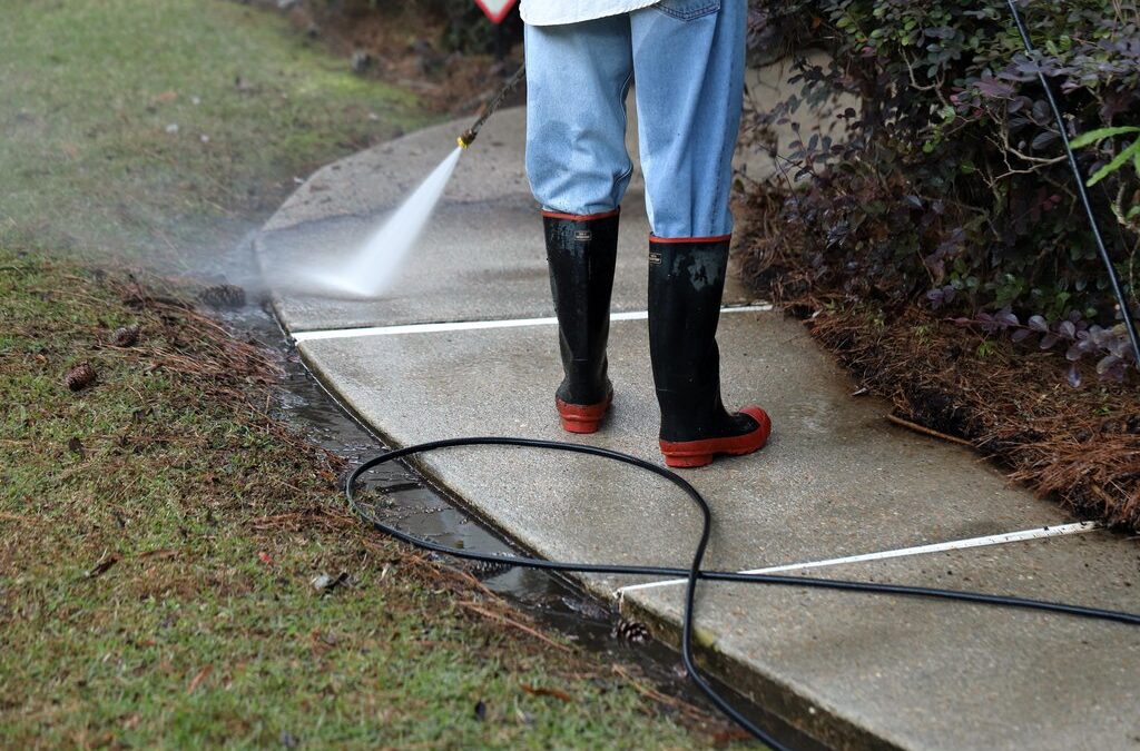 Worker pressure washing sidewalk